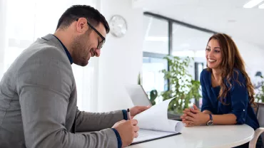 Two people having a conversation at a table in an office.