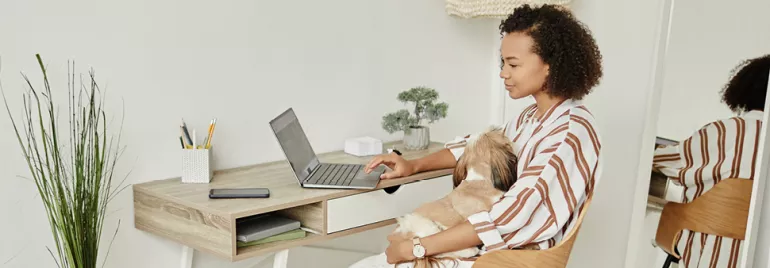 Woman utilizing flexible working options by working remotely from her organized home office, engaging with a laptop. 